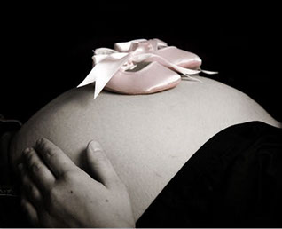 Pregnant woman's belly with baby shoes